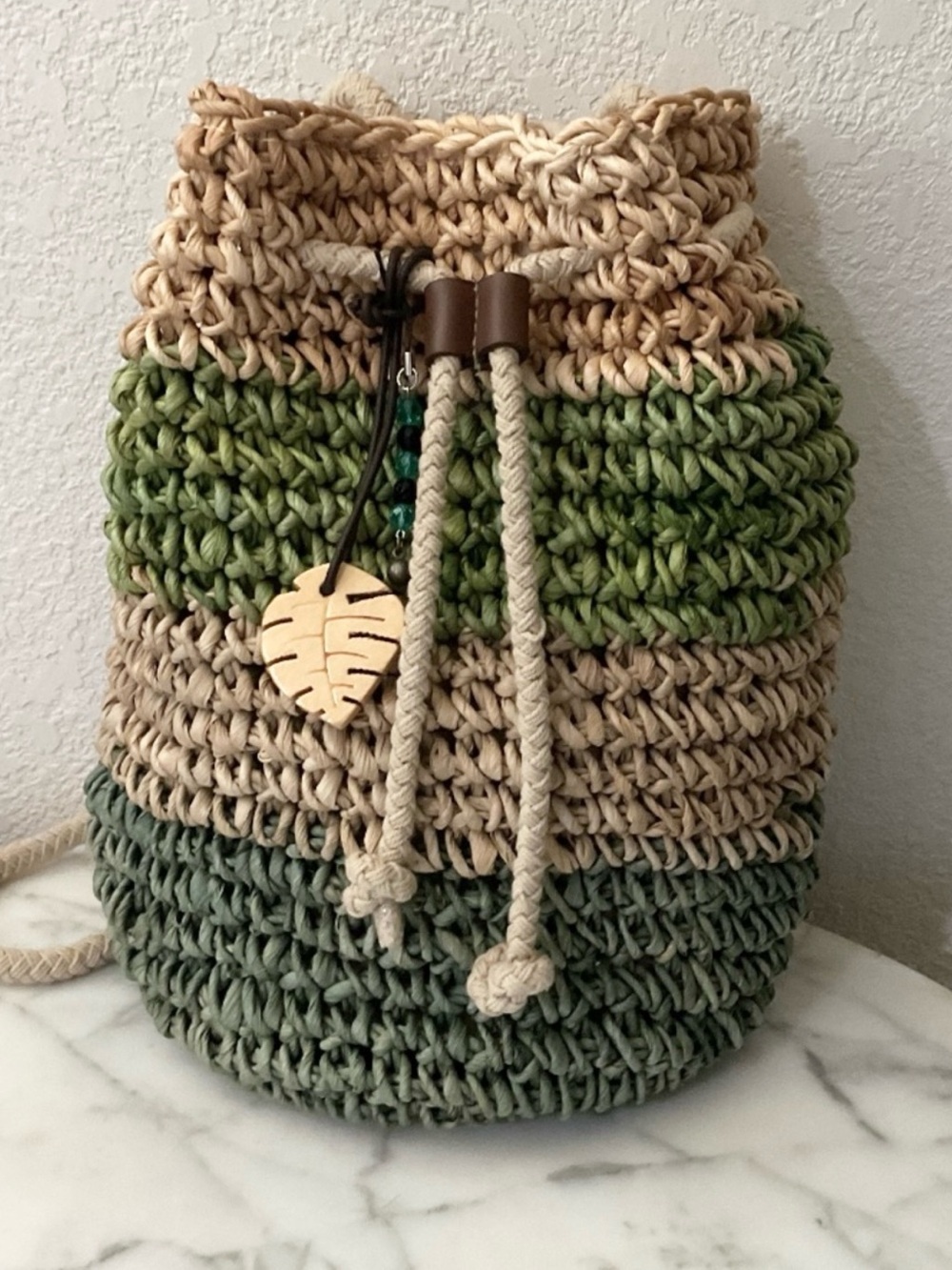 Hand crafted drawstring back pack,artisan style,raffia material,wood leaf charm